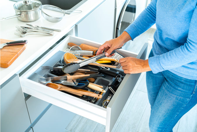 A woman is going through a cooking utensil drawer as she declutters her kitchen