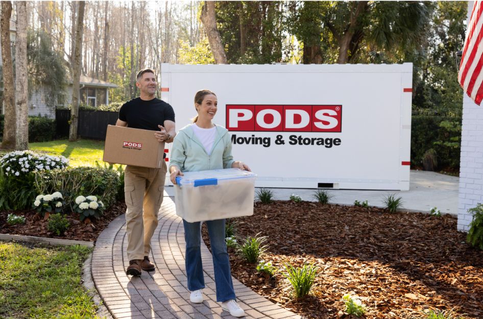 A couple unloads belongings from a PODS container at home, highlighting the flexibility of pack-yourself moving containers.