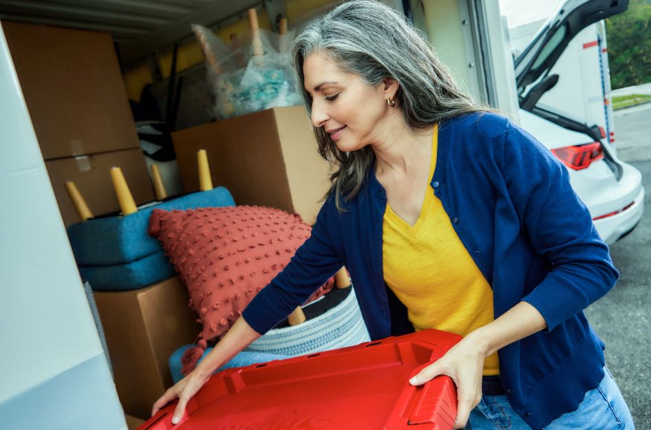 A woman organizes bins and boxes in a PODS container, showcasing packing hacks that help streamline the moving process.
