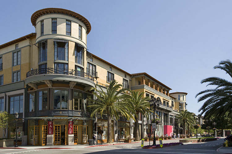 The Santana Row shopping district in San Jose, California. There is a tall, circular building with two red signs that say “SALE” on either side of the wooden door.