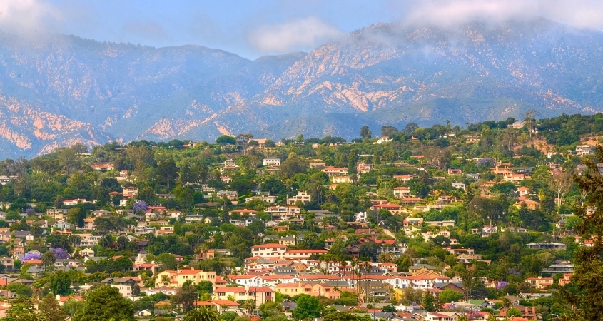 Distant view of the Riviera neighborhood in Santa Barbara, California. In the distance, mountains block a clear blue sky.