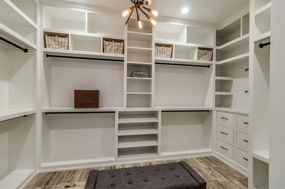 A custom-made closet, part of a full bedroom remodel. The closet is painted white with brown accents and has plenty of cubbies for storage.