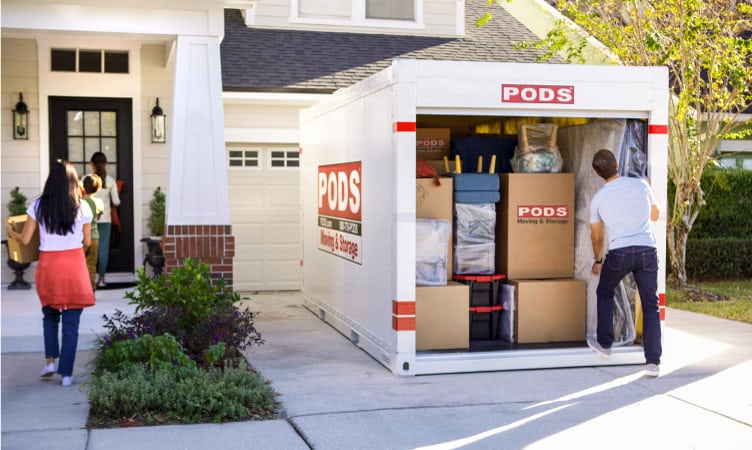A family of four is unloading a PODS container at their new home in one of the best cities near Tampa.