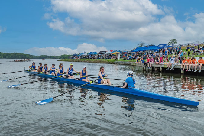 A rowing team in blue uniforms competes during the High Point Rowing Festival in one of the best cities near Winston-Salem, NC