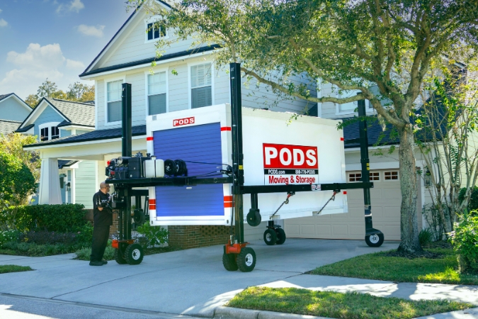 A PODS driver is using PODZILLA to position a portable moving container in a residential driveway for a family living in Grand Rapids, MI.