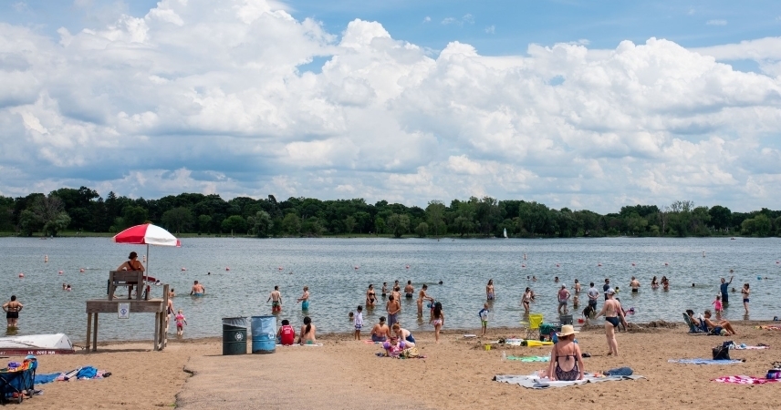 A lifeguard stands watch under a red and white umbrella as dozens of locals relax at one of the many lakes in Minneapolis, Minnesota.
