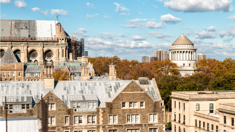 A rooftop view of the buildings in Morningside Heights, one of the safest neighborhoods in New York City. It’s autumn, and Grant’s Tomb is seen in the background amidst copper-colored leaves.