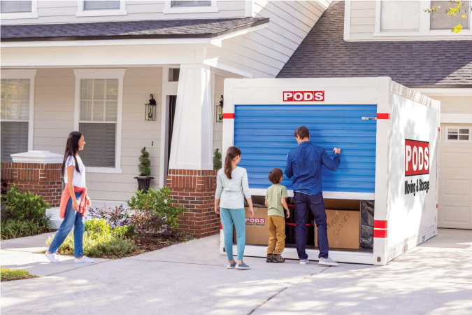 A man closes the blue door on his fully loaded PODS portable moving container as his two kids and wife look on. 