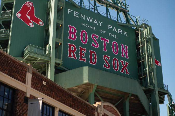 Street-level view of the green and red entry sign at Fenway Park in Boston, Massachusetts.