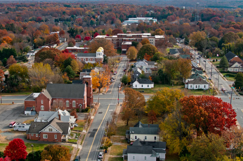 Aerial view of residential Winston-Salem neighborhoods in the fall with beautiful autumnal leaves in hues of red and yellow.