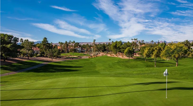 The Canyon Gate Country Club golf course, featuring pristine grass and luxury homes nestled between trees along the edges. 