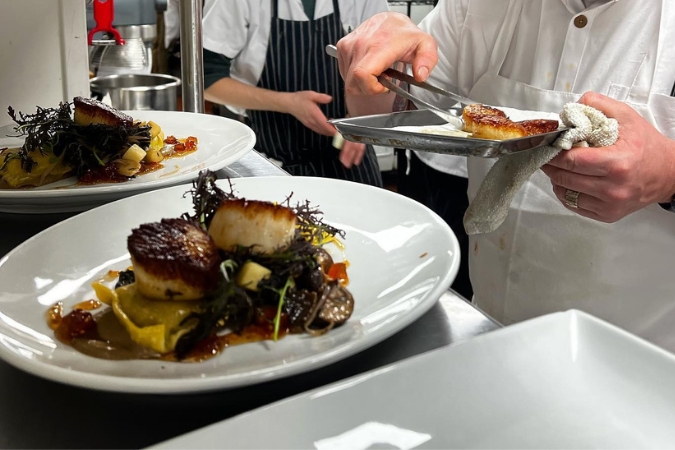 Plated sea scallop entrees being prepared by a chef in the warming area, highlighting the dining experience at restaurants in Bethlehem, PA.