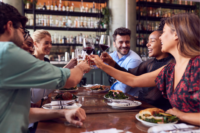 A group of friends are toasting glasses of wine while dining out together in Princeton, Texas.