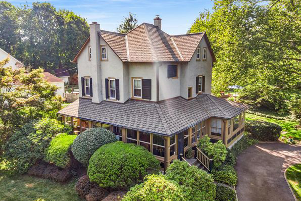a multi-story home in Berwyn, Pennsylvania. It is cream and tan with multiple windows, surrounded by green trees. 