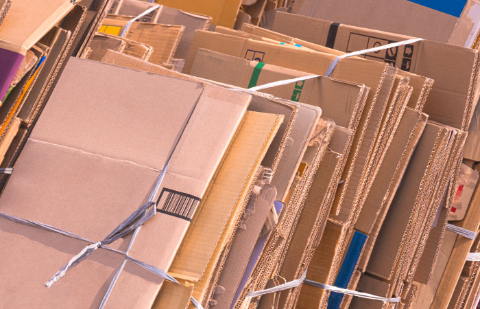 Several bundles of flattened cardboard boxes are tied up with gray string. 