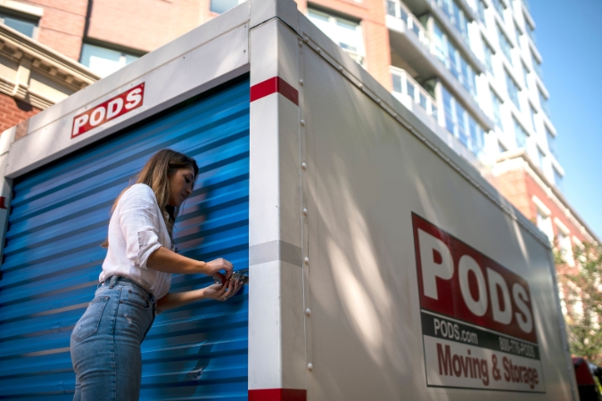 A woman is locking a PODS portable storage container outside a Chicago, Illinois, apartment building — one of the best states for teachers.