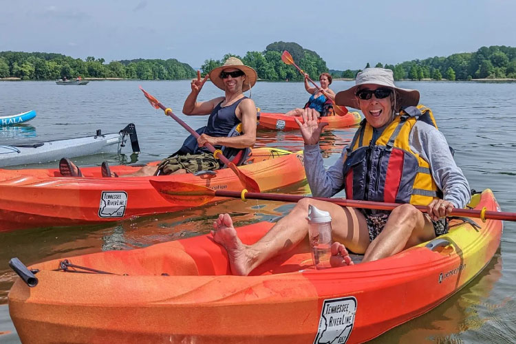 Friends throw up peace signs and big smiles while kayaking on the Tennessee River in Chattanooga, Tennessee.
