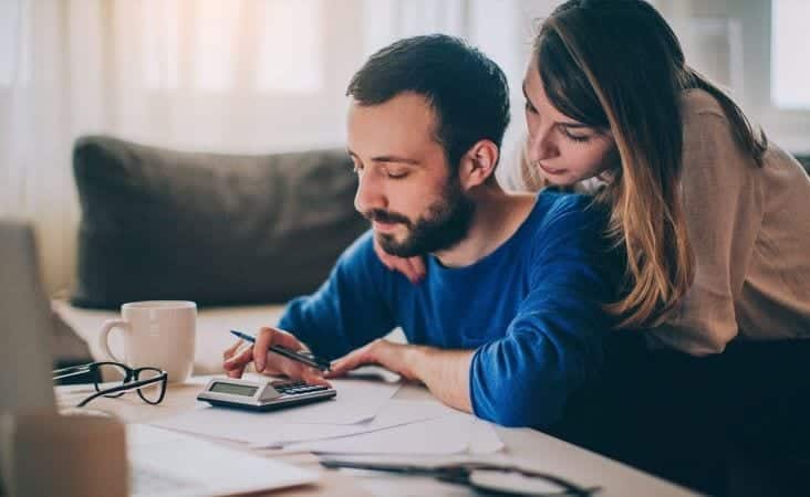 A couple is sitting in their living room and figuring out the budget for their upcoming move.