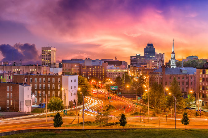 Post-sunset view of the busy streets leading into Downtown — one of the best Worcester neighborhoods — featuring a colorful sky against the city skyline.