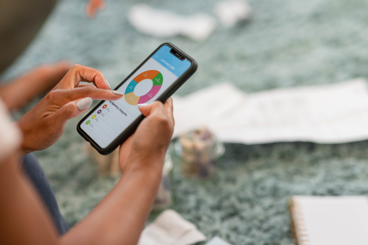 Close-up view of a woman using an app on her mobile phone to track her expenses and plan her budget.