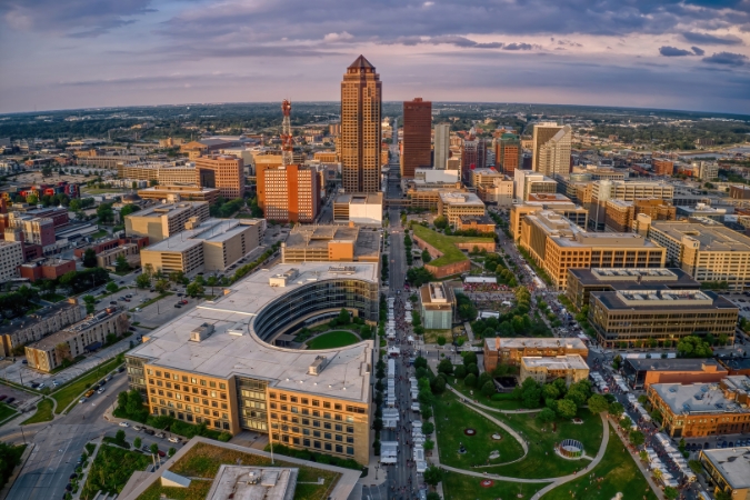 An aerial view of downtown Des Moines, one of the best places to live in Iowa, featuring a cluster of city buildings beneath a cloudy sky.