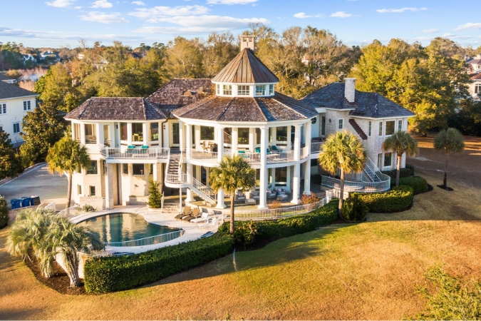A large luxury home with palm trees, wraparound porches, and a backyard pool in Figure Eight Island — one of the best neighborhoods in Wilmington, NC.