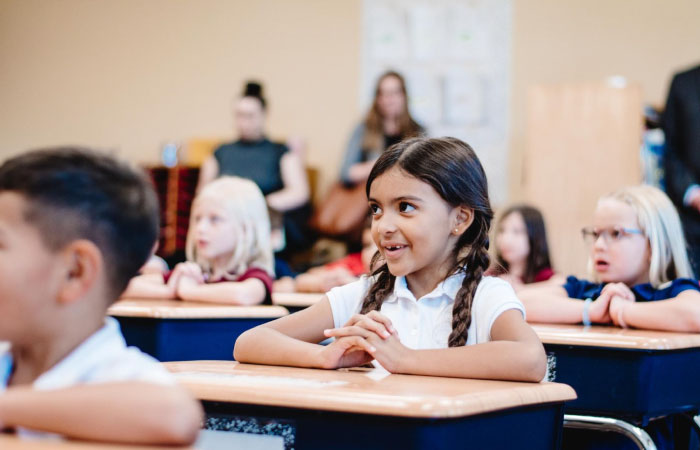 Happy elementary students sit quietly at their desks as they pay attention during class at an elementary school in Gilbert, Arizona.