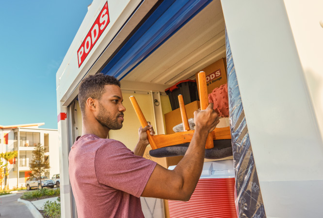  A man is carefully loading his PODS portable moving and storage container. 