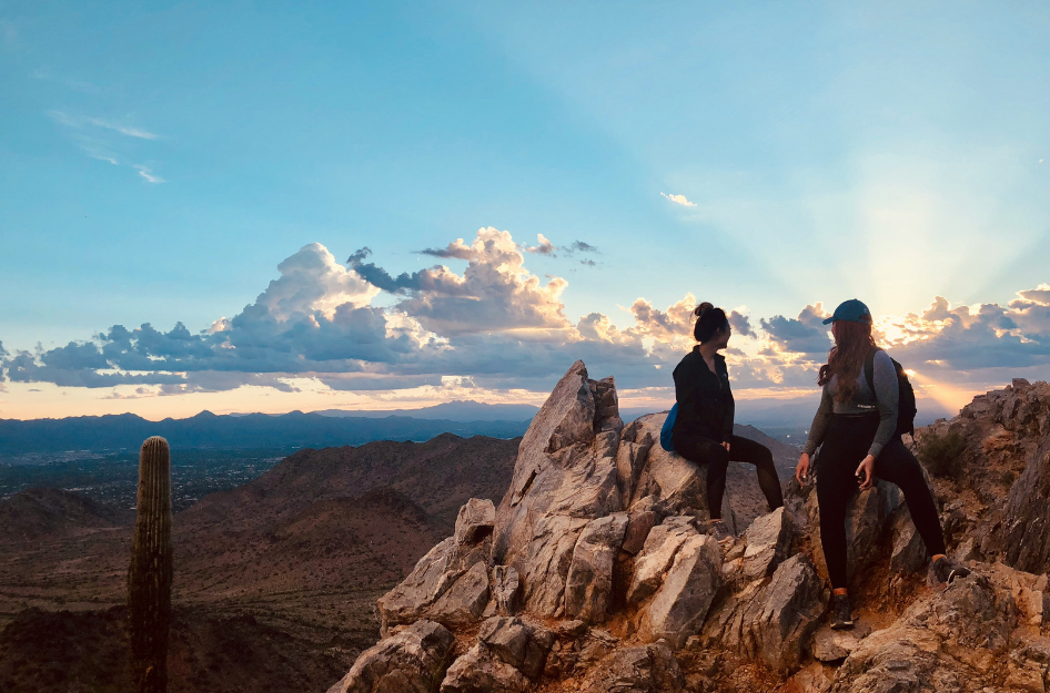 Two hikers sit atop a rock formation, having found a new hobby after moving to Scottsdale, AZ.