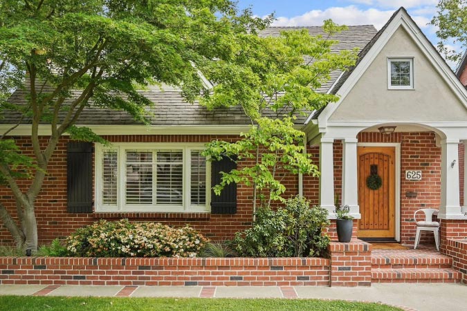 Exterior view of a home in East Sacramento — one of the best neighborhoods in Sacramento — featuring a red brick exterior, covered entryway, and other Tudor-style elements.