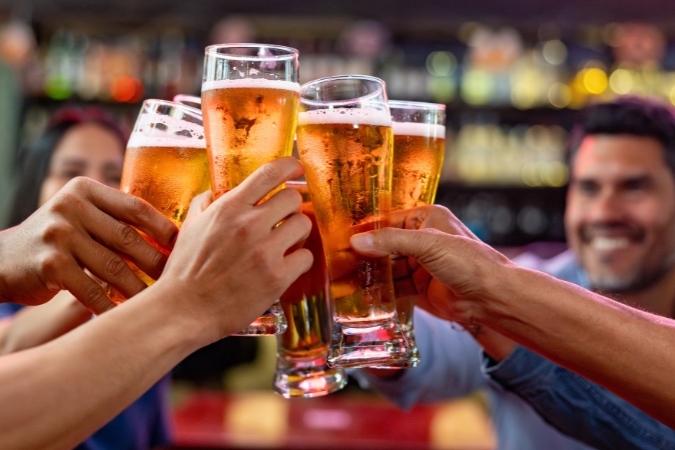  Friends living in Wisconsin clink glasses of beer at a lively bar.