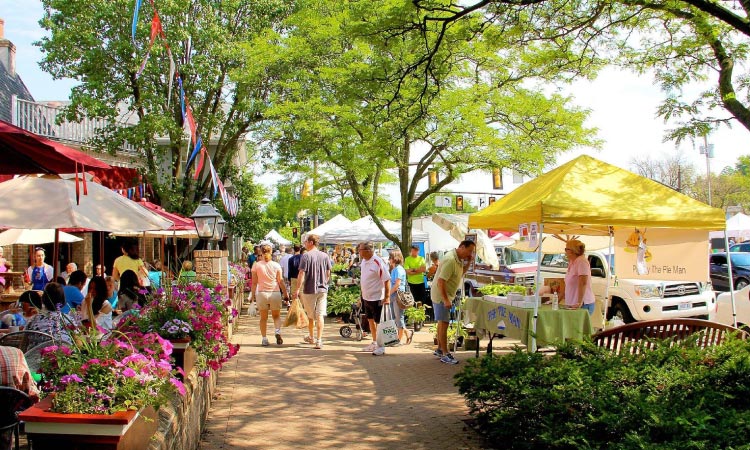 : Locals gather at an event in downtown Worthington, Ohio, on a sunny day.
