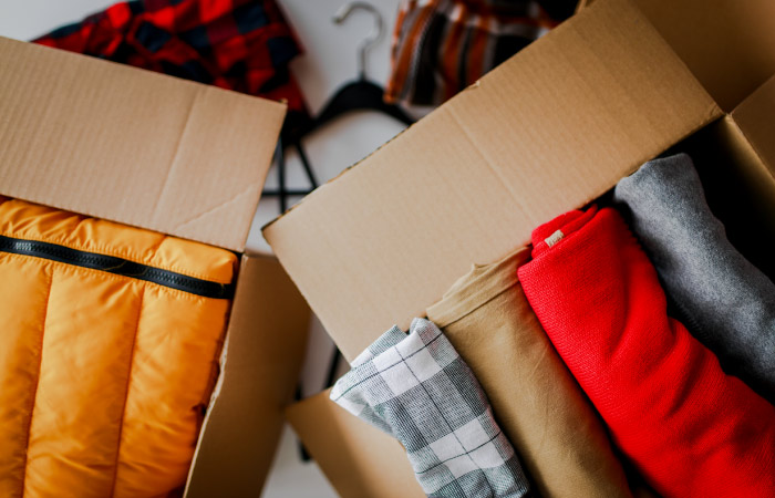 Two moving boxes are neatly packed with clothing items.