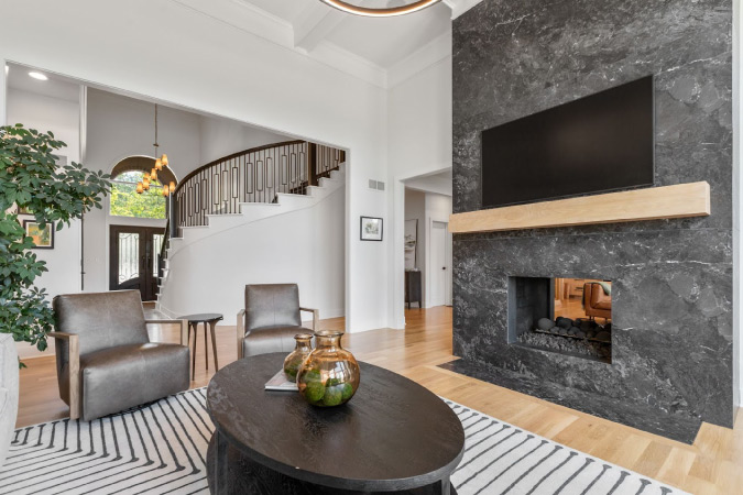 This Scandinavian-style living room features an 18-foot-tall double-sided fireplace made of gray porcelain — an impressive example of home remodeling ideas for homes with high ceilings.