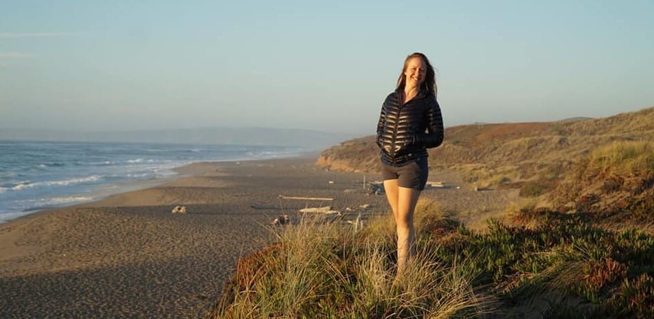 A woman poses for a photo atop some seaside bluffs. 