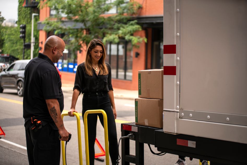 A young woman stands with her PODS City Service truck driver. PODS City Service is a great resource for Boston moving services.