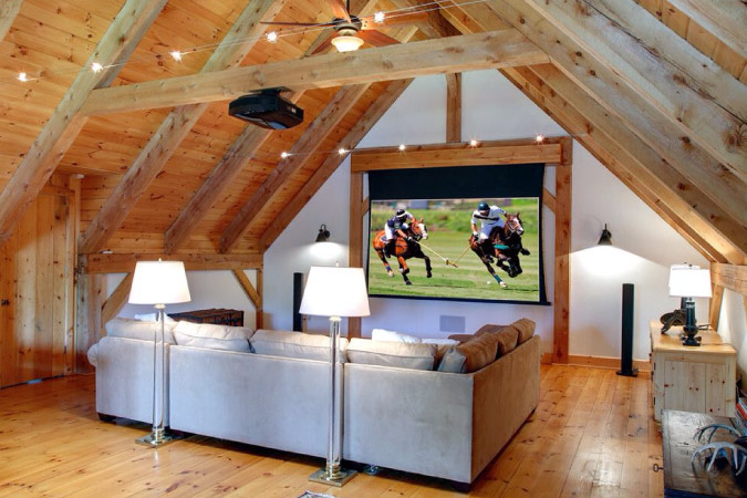 An attic that’s been converted into a living room with a projector screen. 
