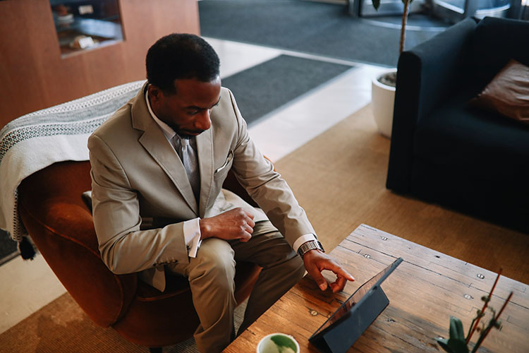 A man in a New York City hotel lobby, checking emails on his tablet