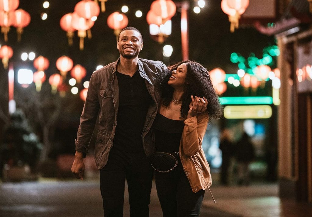 A handsome couple walk with their arms around each other as they explore the night life in Los Angeles.