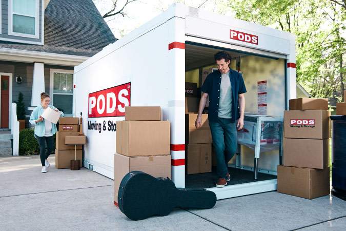 A man and his pregnant wife are in the process of loading a PODS portable moving container as they prepare for moving to Fresno, California.