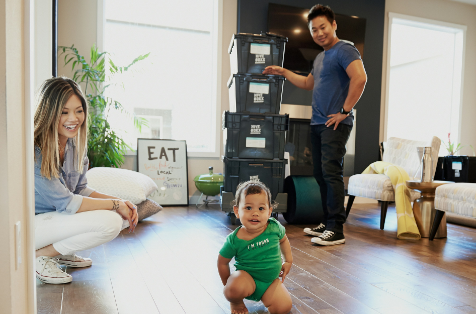 A young couple smiles as they pack and prepare to move with a baby.