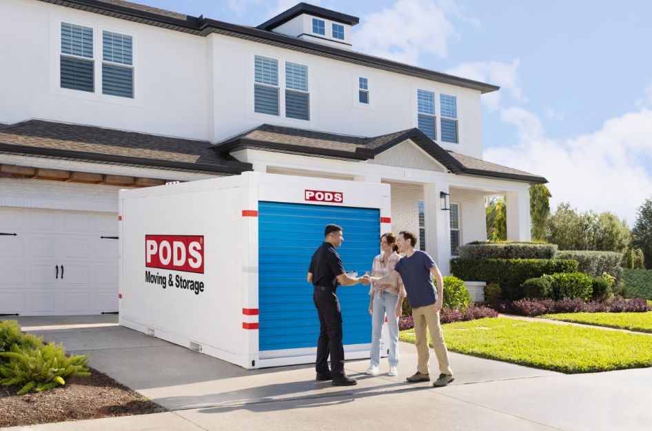 A PODS container sits in a driveway as customers speak with a PODS representative, showing how long-term storage can work at home.