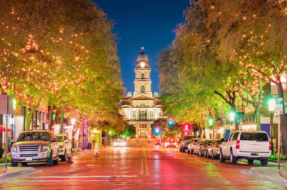 An evening view down an illuminated brick road in downtown Fort Worth, Texas.