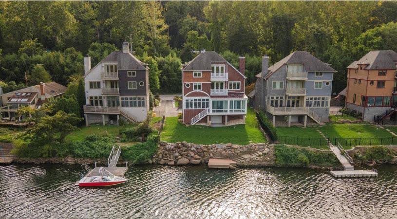 Multi-story waterfront homes back up to lush green yards and floating docks in Gladwyne, Pennsylvania — one of the cities close to Philadelphia.