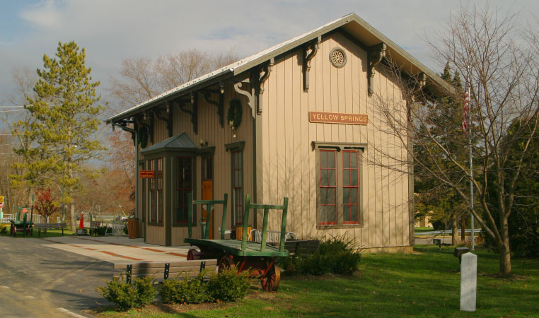 A historic-looking building in Yellow Springs, OH. It’s painted a beige color with green accents and there’s a sign on the side of the building that says, “YELLOW SPRINGS.”