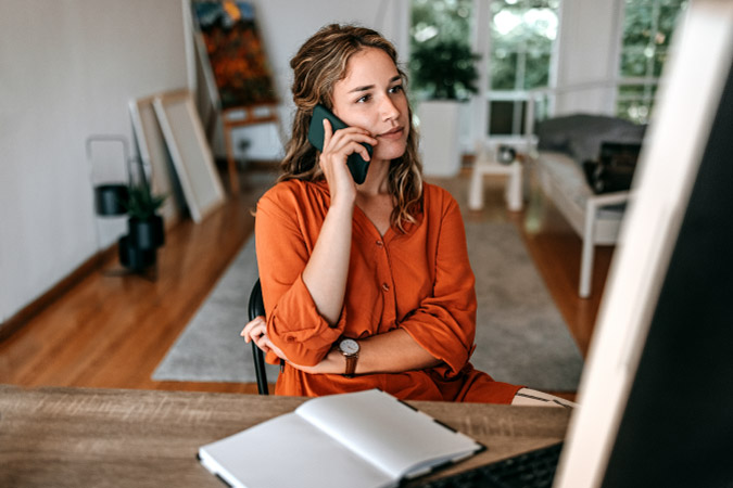 A woman is talking with a moving company on her mobile phone, planning details of her upcoming PCS to Hawaii.