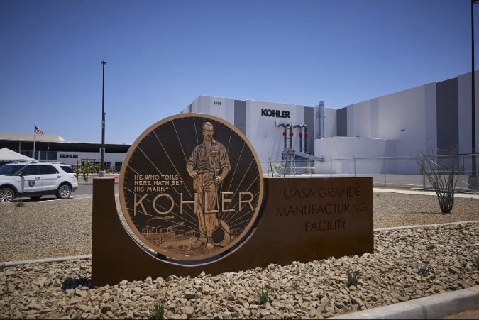 Exterior view of the Kohler Co. manufacturing facility in Casa Grande, AZ, featuring a metal sign and a large warehouse-style building in the background.
