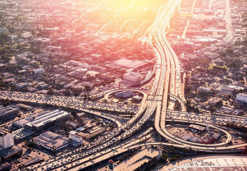 A busy highway in Los Angeles, California. The roads loop and the cars sit in bumper to bumper traffic.