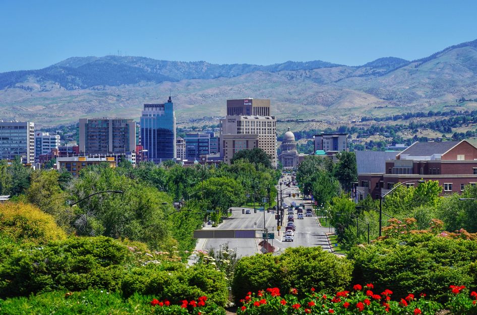 Ariel view of sunny Downtown — one of the best neighborhoods in Boise — featuring a combination of brick city buildings and mountains in the background.