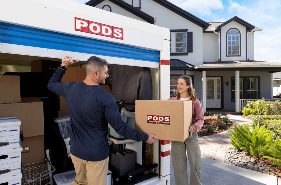 A couple loads boxes into a PODS container in their driveway, showing how stress free moving can start at home.